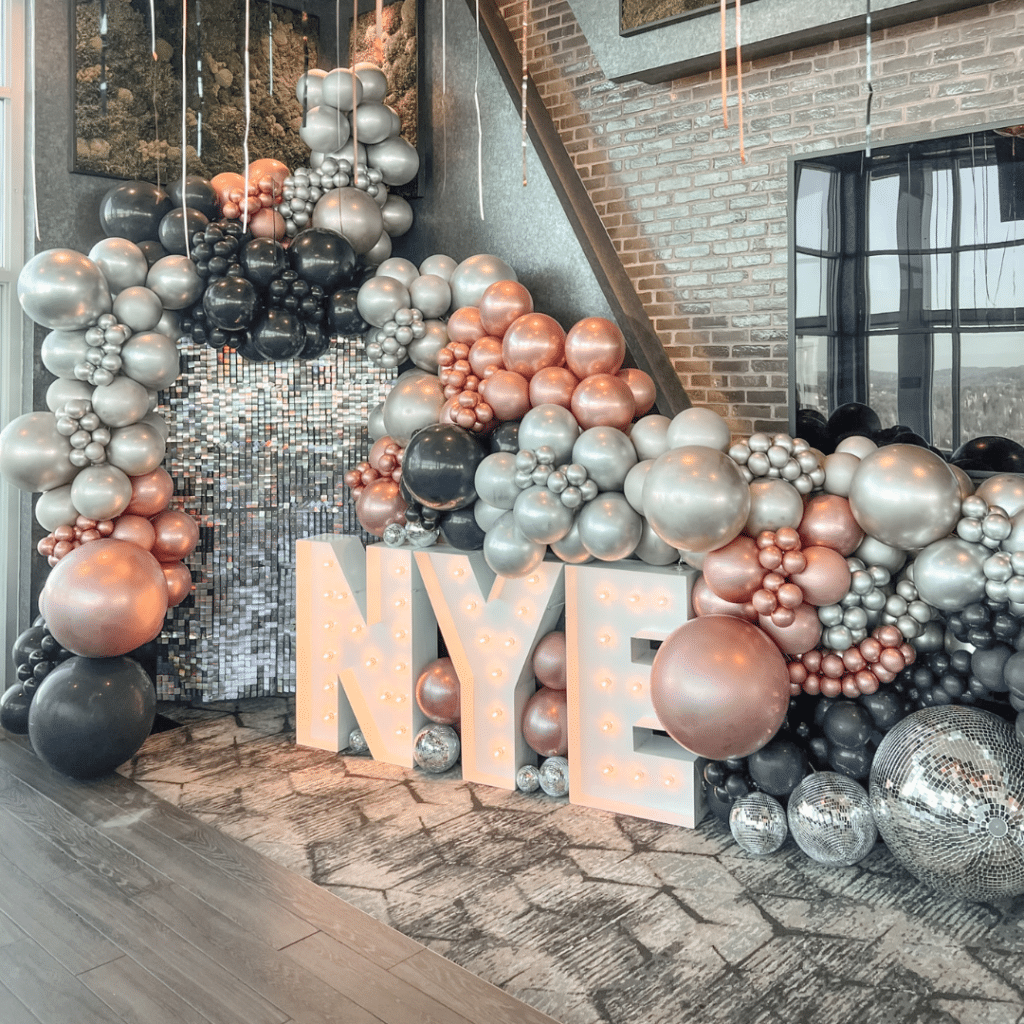 Marquee letters spelling out "NYE" beside a balloon display
