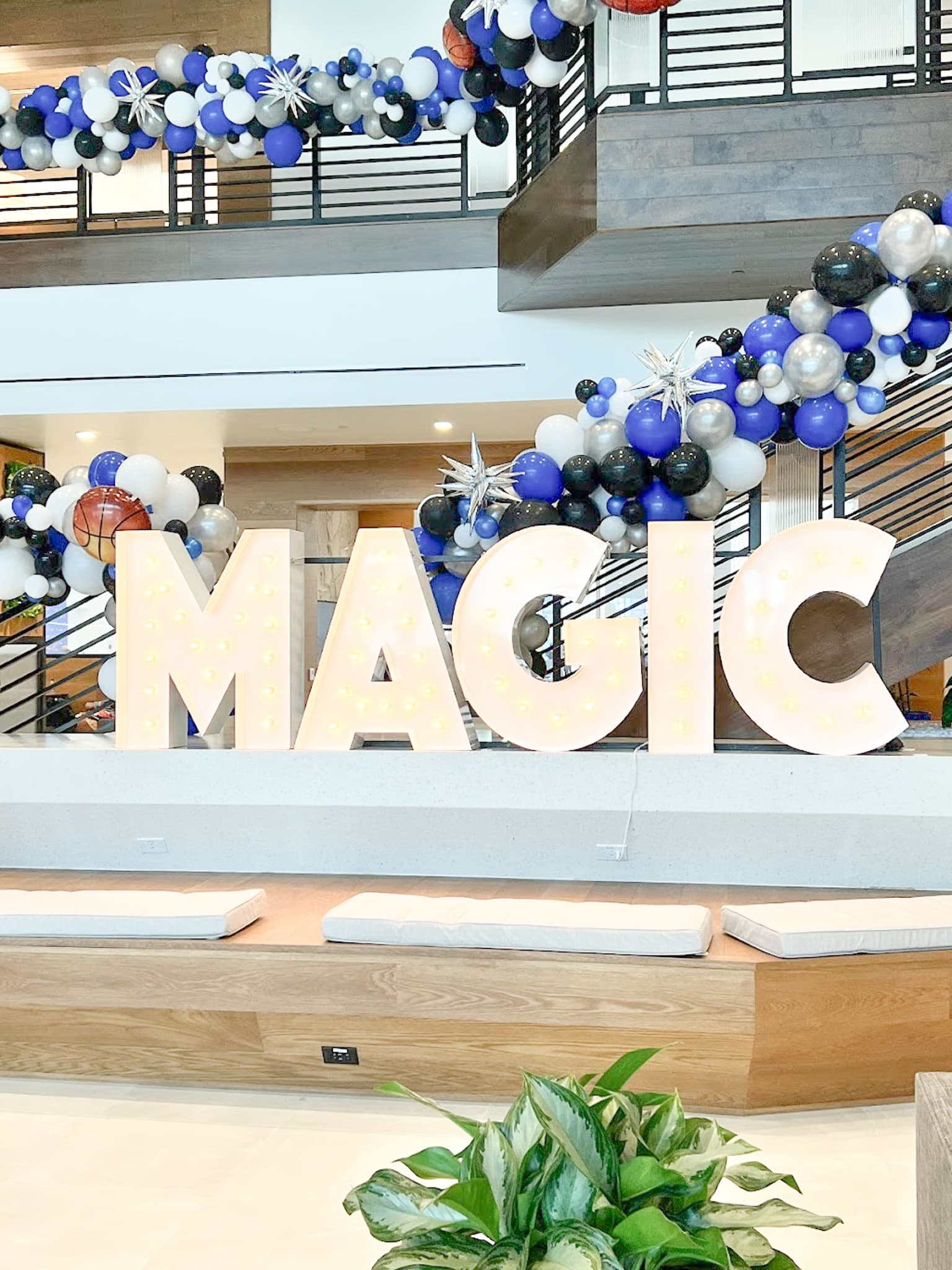 Marquee Letters spelling out MAGIC beside blue, silver, black, and white balloons