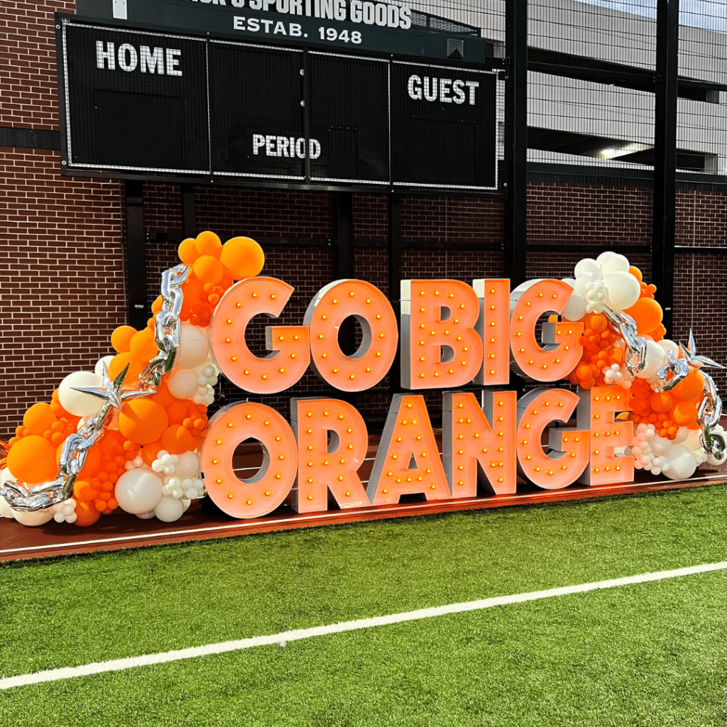 Marquee letter display that reads "GO BIG ORANGE" with orange and white balloons