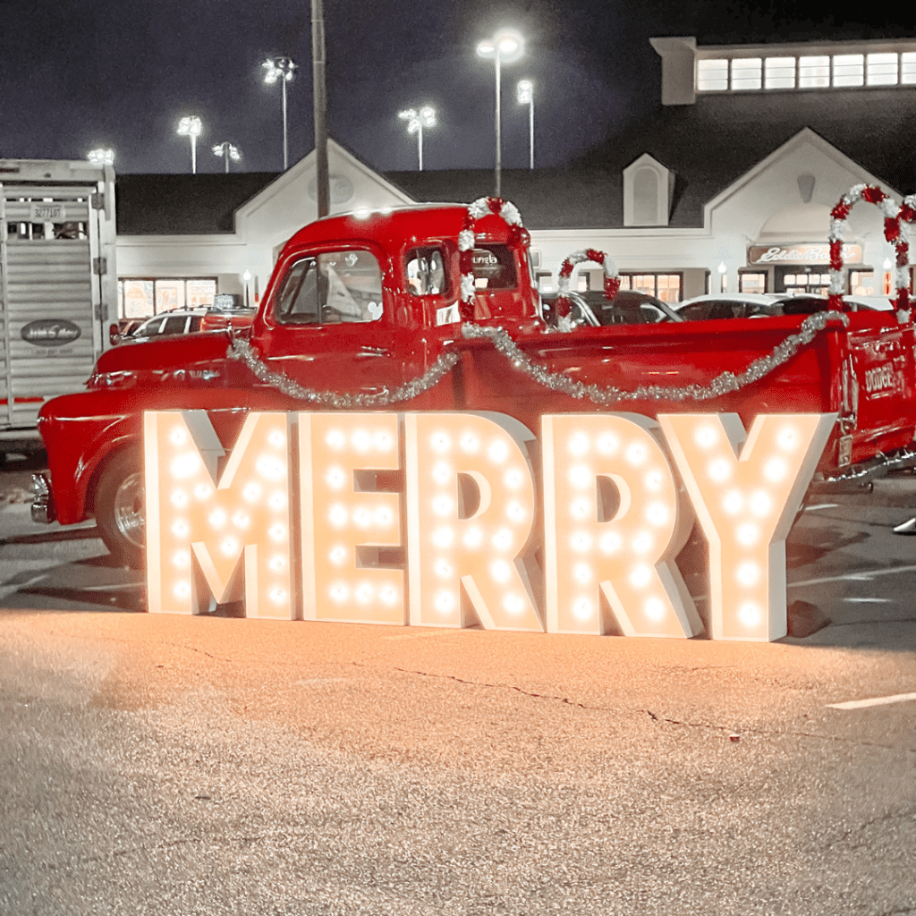 Light Up Letters spelling out MERRY in front of a red truck