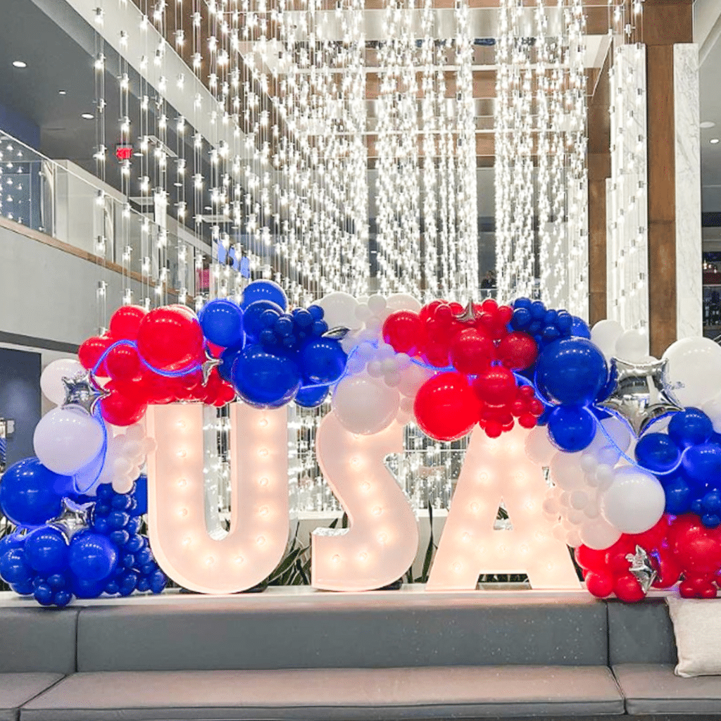 USA spelled out in marquee lights with red, white, and blue balloons