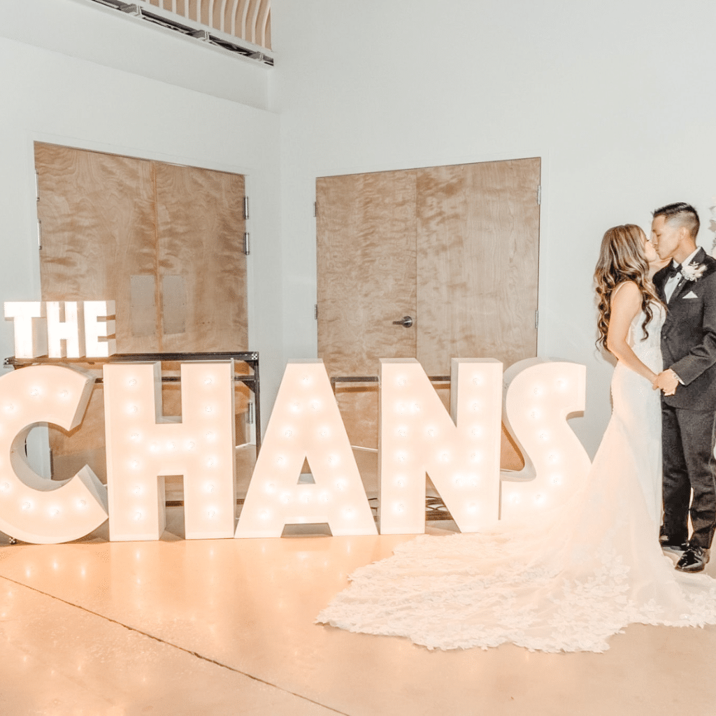 Marquee Letters spelling out "The Chans" beside a bride and groom kissing