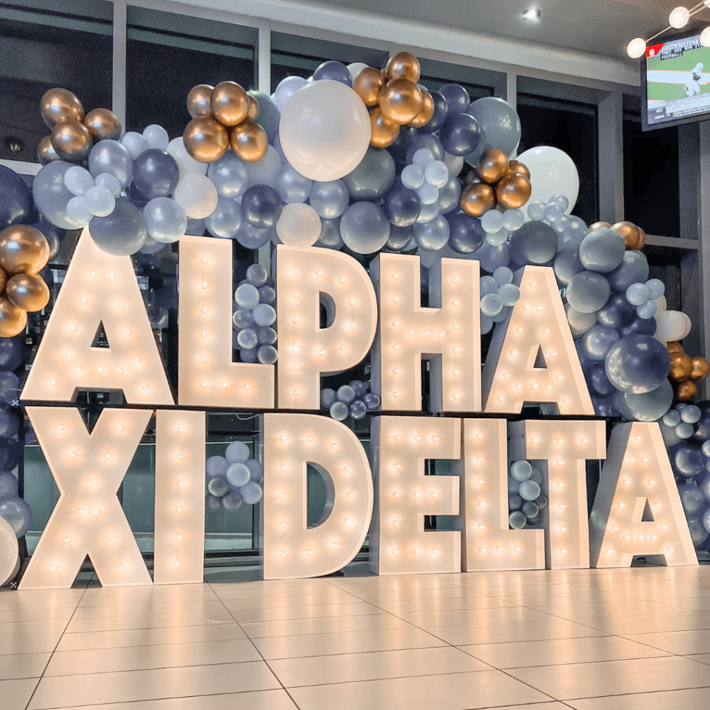 Light up letters spelling out ALPHA XI DELTA surrounded by blue and gold balloons
