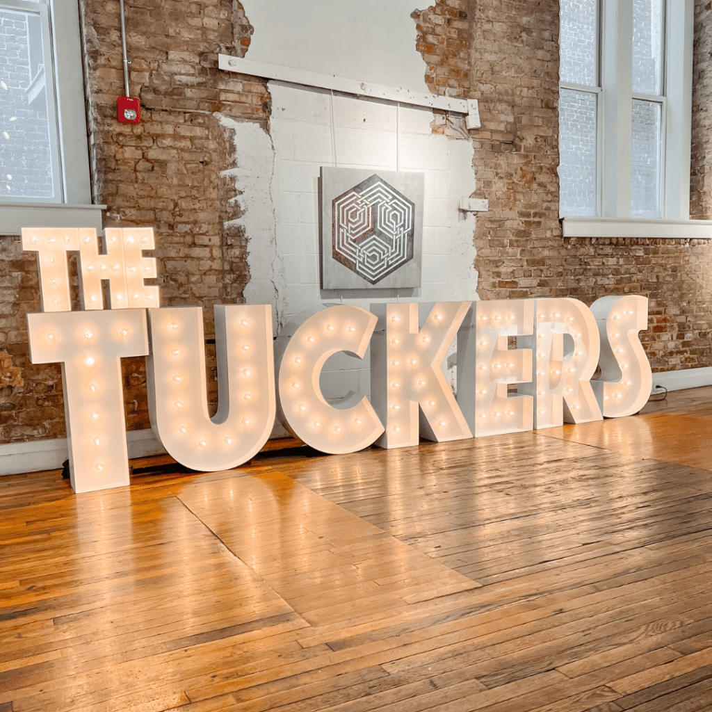 The Tuckers in marquee lights on a wooden floor