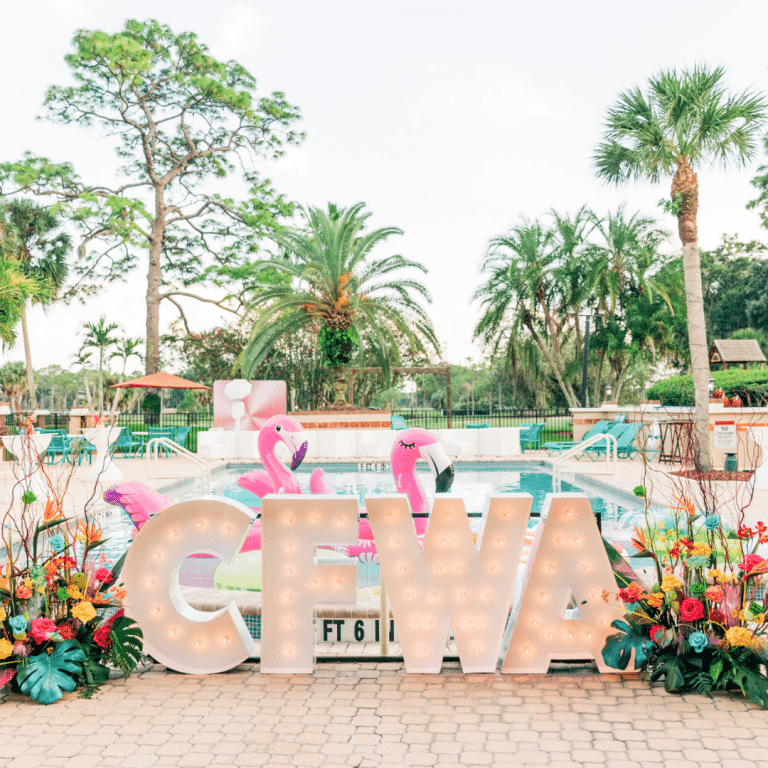 CFWA is spelled out in marquee lights. The letters are surrounded by flowers and inflatable flamingos