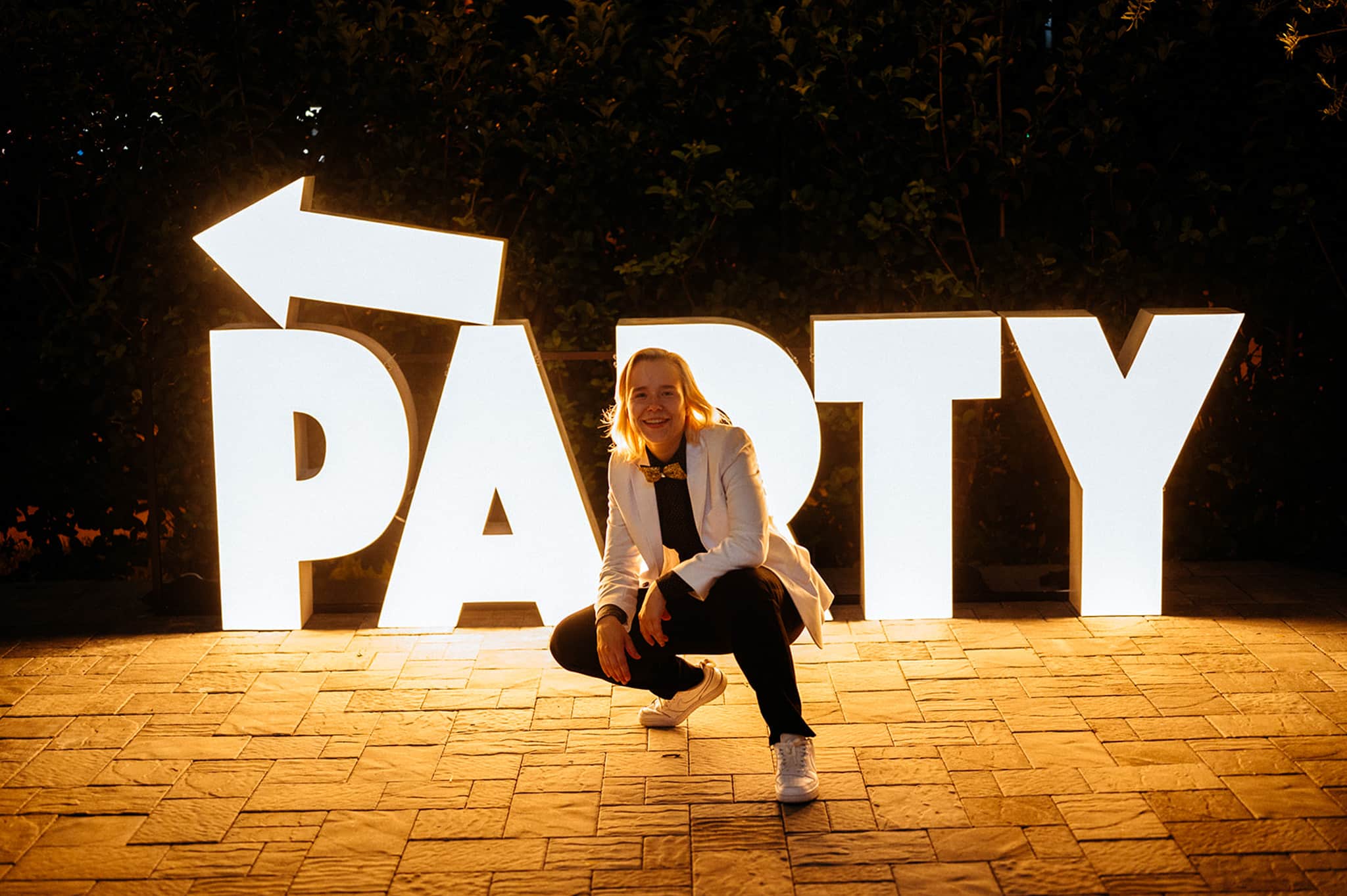 person posing in front of Light-Up Marquee Letters that read PARTY with an arrow