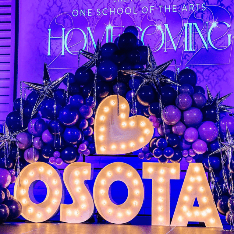 A heart symbol and the word OSOTA in marquee lights surrounded by purple and silver balloons